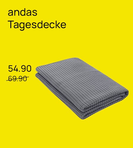 andas Tagesdecke 54.90 statt 69.90 – gefaltete graue Tagesdecke auf gelbem Hintergrund