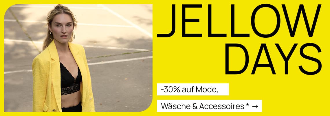 -30 % auf Mode, Wäsche & Accessoires – Frau in gelbem Blazer und schwarzem Top vor einem Parkplatz