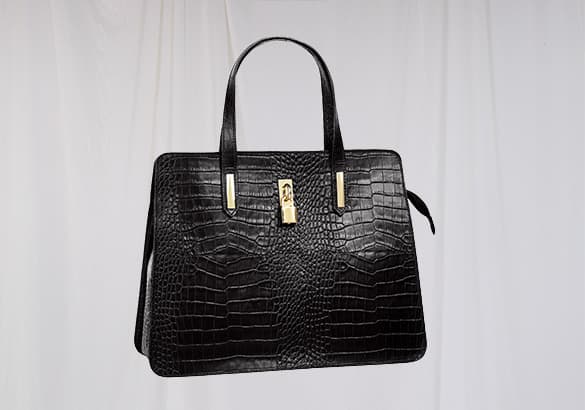 Schwarze Handtasche mit Kroko-Muster und goldfarbenem Verschluss vor weißem Hintergrund.