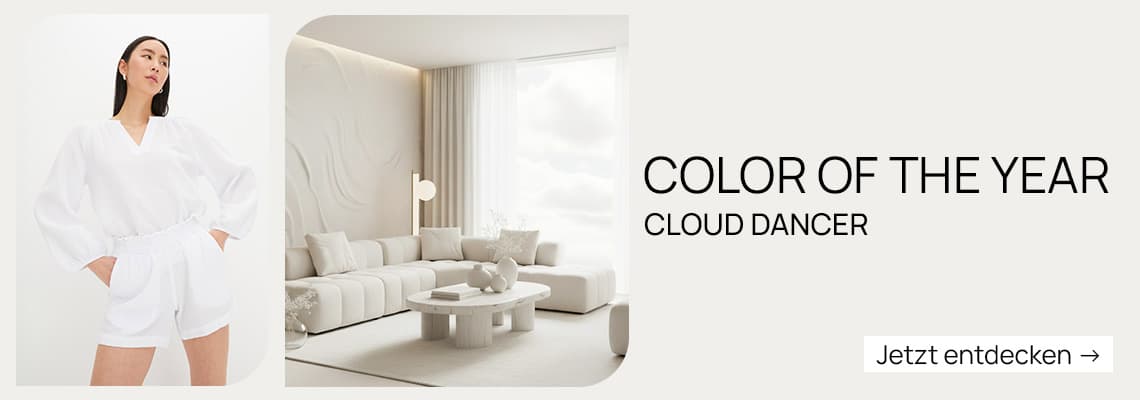 COLOR OF THE YEAR CLOUD DANCER – Frau in weißem Outfit neben elegantem, weißem Wohnzimmer. Jetzt entdecken →