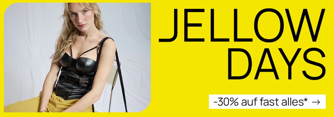 JELLOW DAYS –30 % auf fast alles* – Frau im schwarzen Top sitzt vor gelbem Hintergrund und schaut in die Kamera